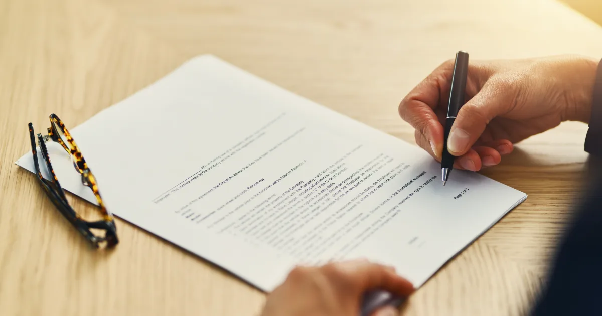Carpeta de contratos laborales abierta sobre un escritorio junto a un calendario con fechas marcadas